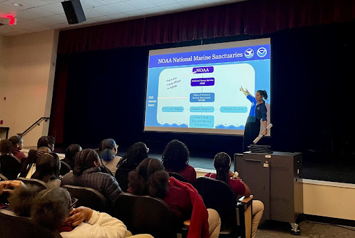 A person giving a presentation. The screen on the presentation reads: NOAA National Marine Sanctuaries