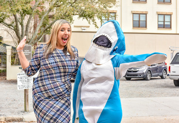 A person standing next to someone in a shark costume.