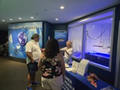 Woman talks to a family in front of a table with outreach materials.