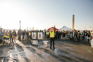A group of volunteers are gathered to listen to a speaker using a megaphone.