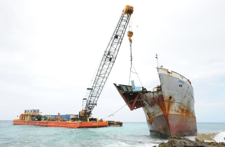 Response crews at shore are removing sections of a 202-foot grounded freighter to prepare the vessel for removal in calm waters.