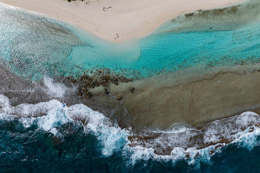 An aerial image of waves crashing along a shoreline. 