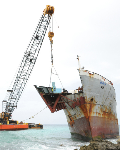 Response crews at shore are removing sections of a 202-foot grounded freighter to prepare the vessel for removal in calm waters.