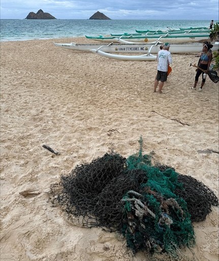A pile of removed derelict fishing nets sits on a sandy beach. 