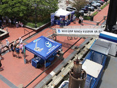 Image of a ship, blue tent, and people on a street