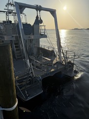 The stern of a ship reading RV Gannet with the sun behind it.