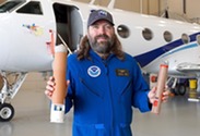 A NOAA electronics engineer holds up two dropsondes
