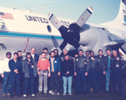 A group of people standing in front of NOAA WP-3D Orion nicknamed Kermit