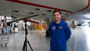 NOAA engineer Nick Underwood standing with a NOAA WP-3D Orion and an uncrewed aircraft system