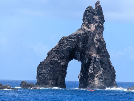 Small boat in front of a rock arch in the Norther Mariana Islands - LCDR Kell Bliss