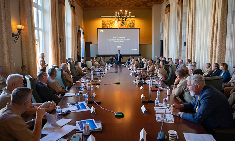 Members of the NPS community and Pac Fleet leadership sit around a large conference table. 