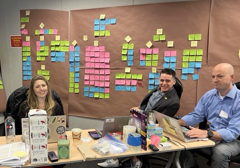 OAG facilitators sit in front of a brainstorming board of sticky notes. 