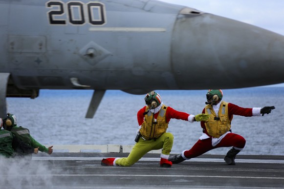 Sailors launch an F/A-18E from the flight deck of  CVN_72  in holiday outfits.