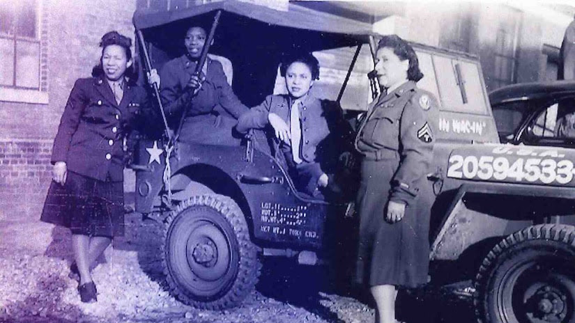 Black women soldiers stand by a jeep in the 1940s