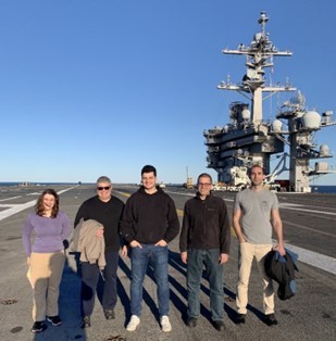 Five researcher stand on the deck of the USS Carl Vinson.