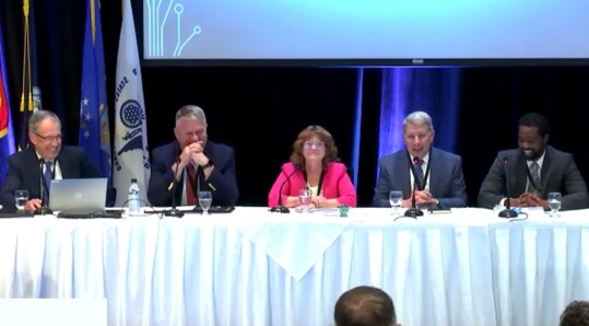 Panel members sit at a table