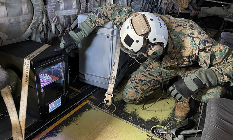 Marine checks a 3D printer strapped as cargo on an MV-22 Osprey