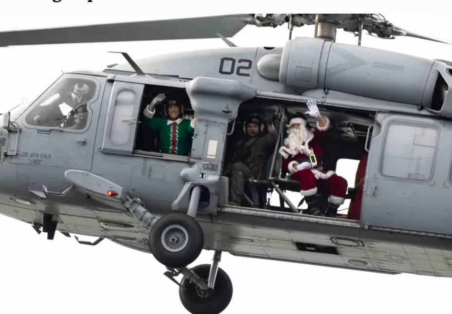 Santa Claus waves from aboard an MH-60S Seahawk helicopter.
