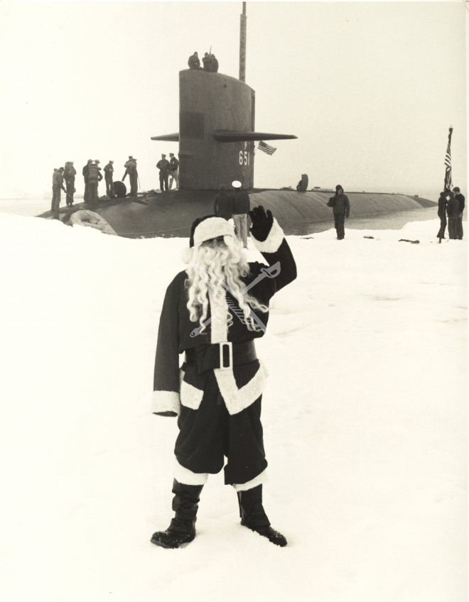 Santa waving in front of a submarine partially submerged in ice