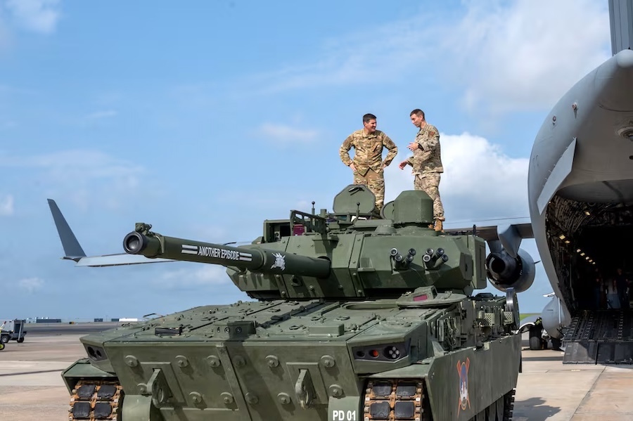 two soldiers in fatigues standing on top of a tank
