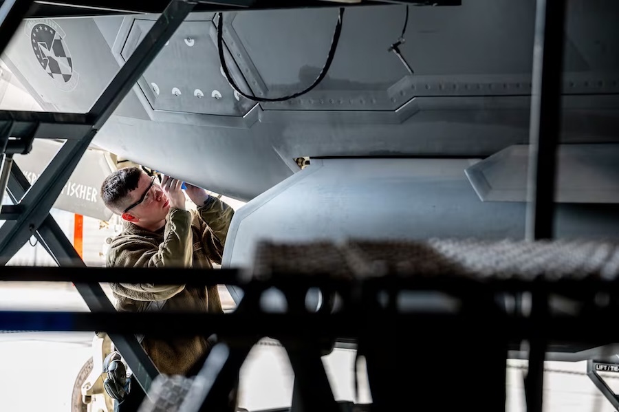 airman crouched beneath a plane