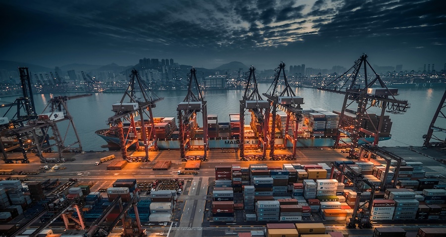 shipping dock with cargo containers, lit up by street lights, dark cloudy sky in background