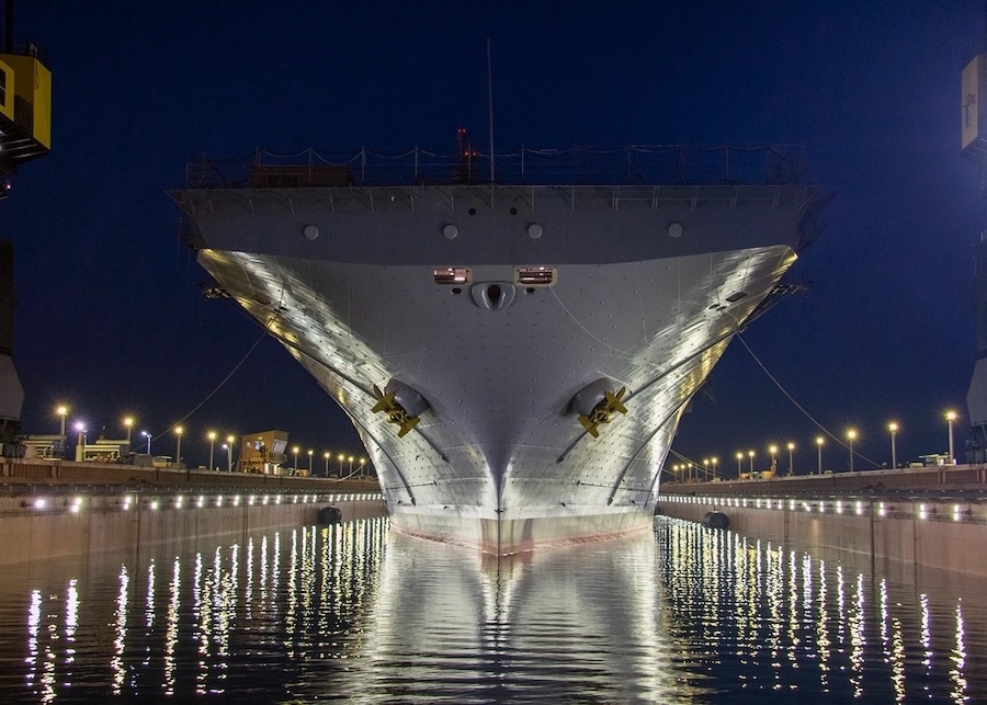 stern of a ship at night, lit from below, with lights reflecting on the water