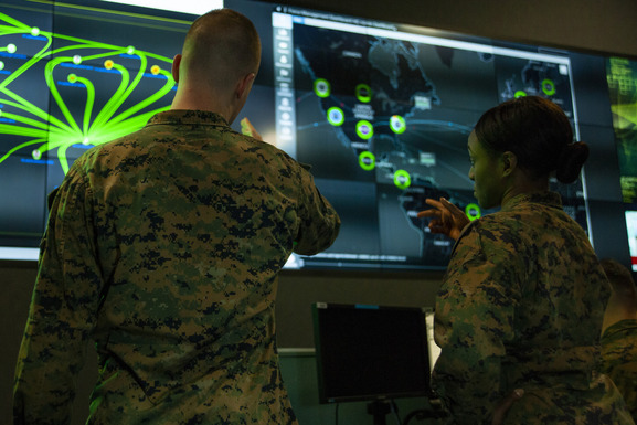two marines looking at large computer screens 