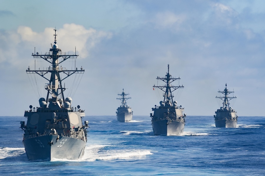 four ships headed toward viewer on blue ocean