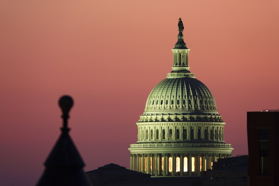 The Capitol dome at sunset, against an orange sky