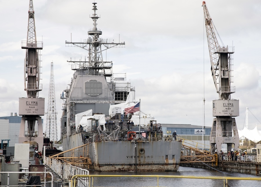 ship seen from the rear, in dock with cranes on either side