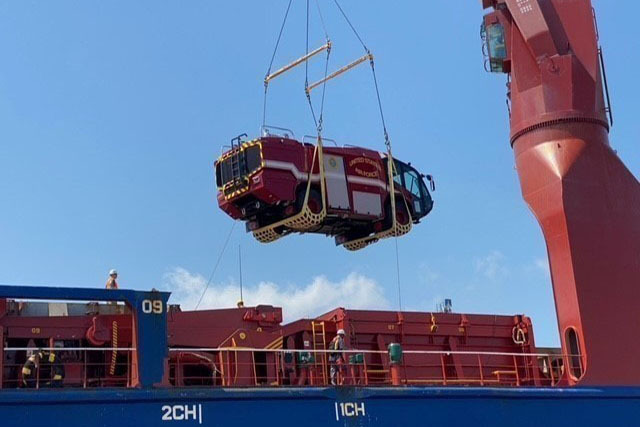 Vehicle suspended by a crane, being loaded to a ship