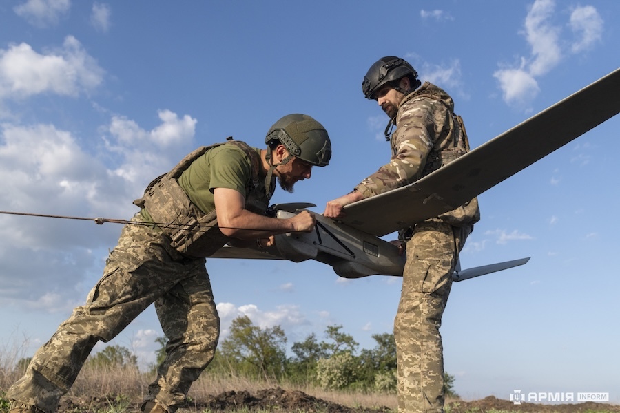 two soldiers holding a large black drone