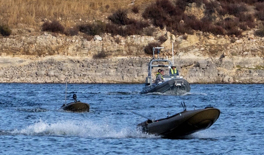NPS-JIFX two uncrewed surface vessel near shore followed by a small manned boat