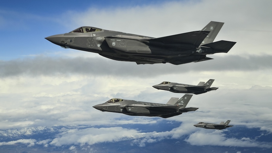 4 black F-35A fighter jets fly in formation above the clouds