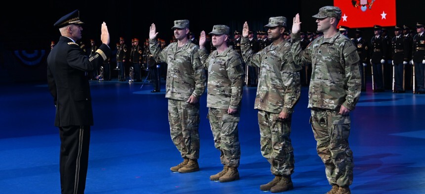 four soldiers with right hands raised, facing a uniformed officer