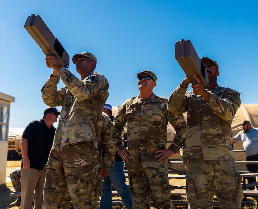 men in fatiques holding rectangular anti-drone guns aloft