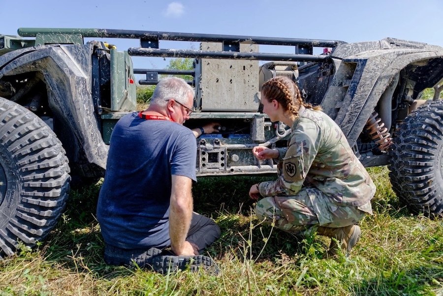 man and woman crouched at side of autonomous ground vehicle