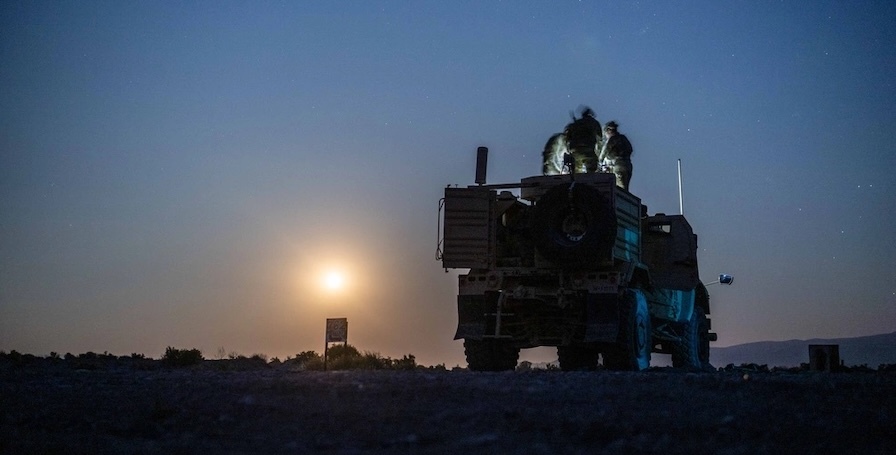 navy seals on top of a truck, dark sky, sun on horizon