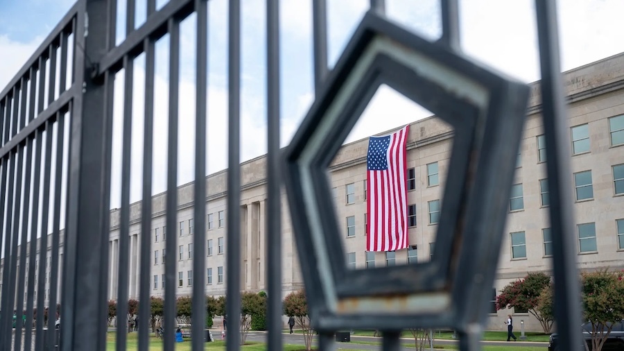 pentagon building with flag seen through a fence