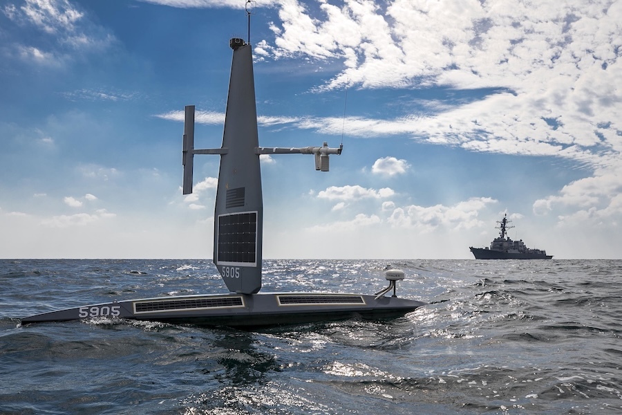 unmanned surface vessel at sea with destroyer in background