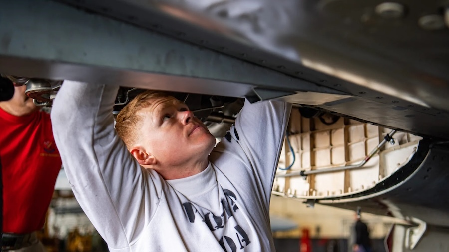 mechanic working below a jet