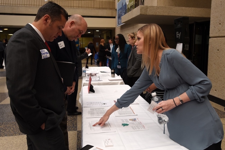 A woman points out print to two conference attendees