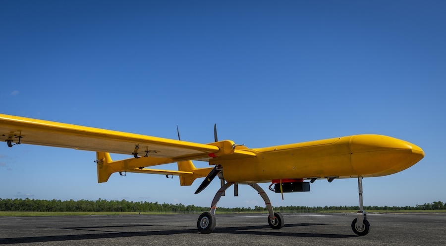 bright yellow aircraft sits on a runway, bright blue sky in background