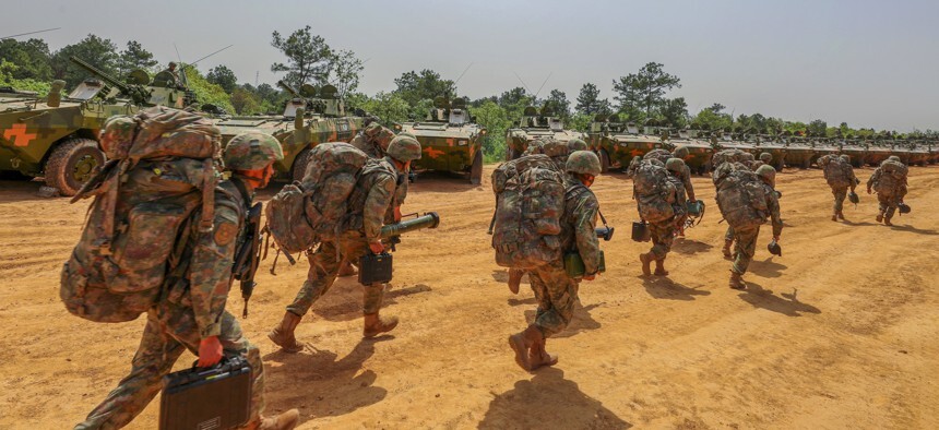 troops in fatigues carry large rucksacks and other equipment