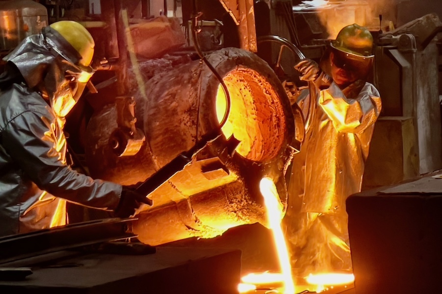 two workers pour molten metal