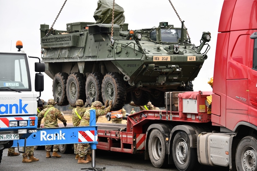 soldiers loading a tank on the bed of a truck