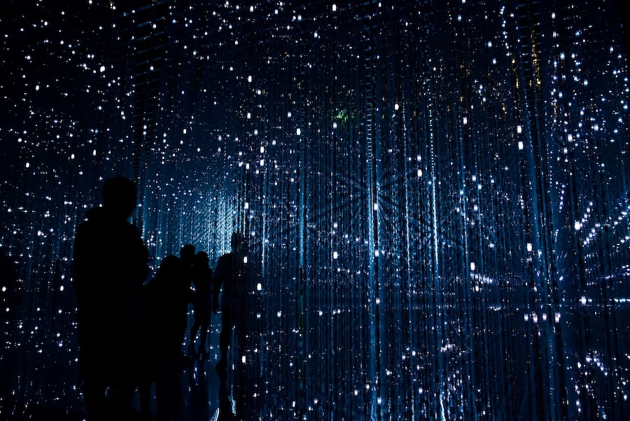 People silhouetted in front of an array of blue and white lights_robynne-o-HOrhCnQsxnQ-unsplash