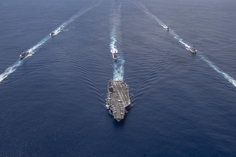 aircraft carrier flanked by smaller ships