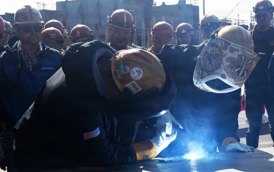 two people in helmet's bent over a welding torch